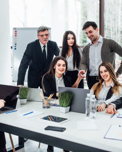 Staff meeting. Group of   young modern people in smart casual wear discussing something while working in the creative office . Business time..